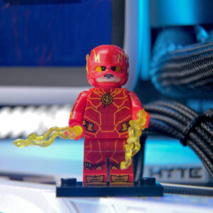 Farklı açılardan çekilmiş LEGO Flash anima figürü, parlak kırmızı ve sarı detaylarla, enerjik ve dinamik bir görünüm sergiliyor. Arka planda bilgisayar ve kablolar yer almakta, oyuncu ve oyun temalı ortam vurgulanıyor.